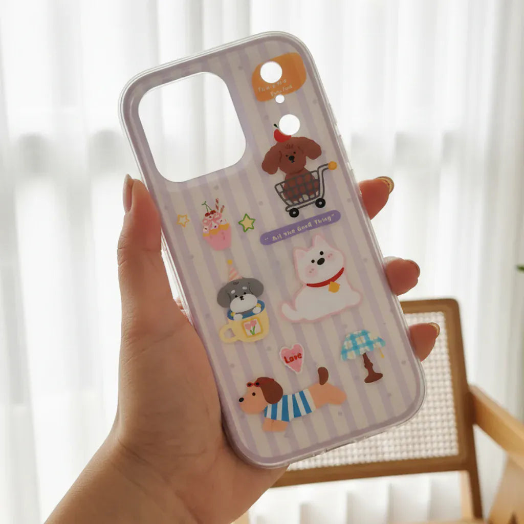 Phone case with cartoon characters held by a hand against a blurred green outdoor background