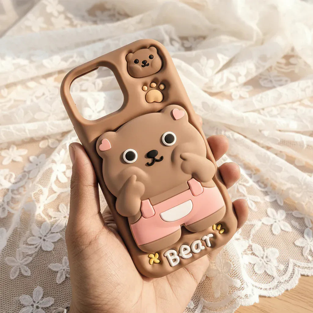 Phone case shaped like a bear held in a hand with a blurred outdoor background