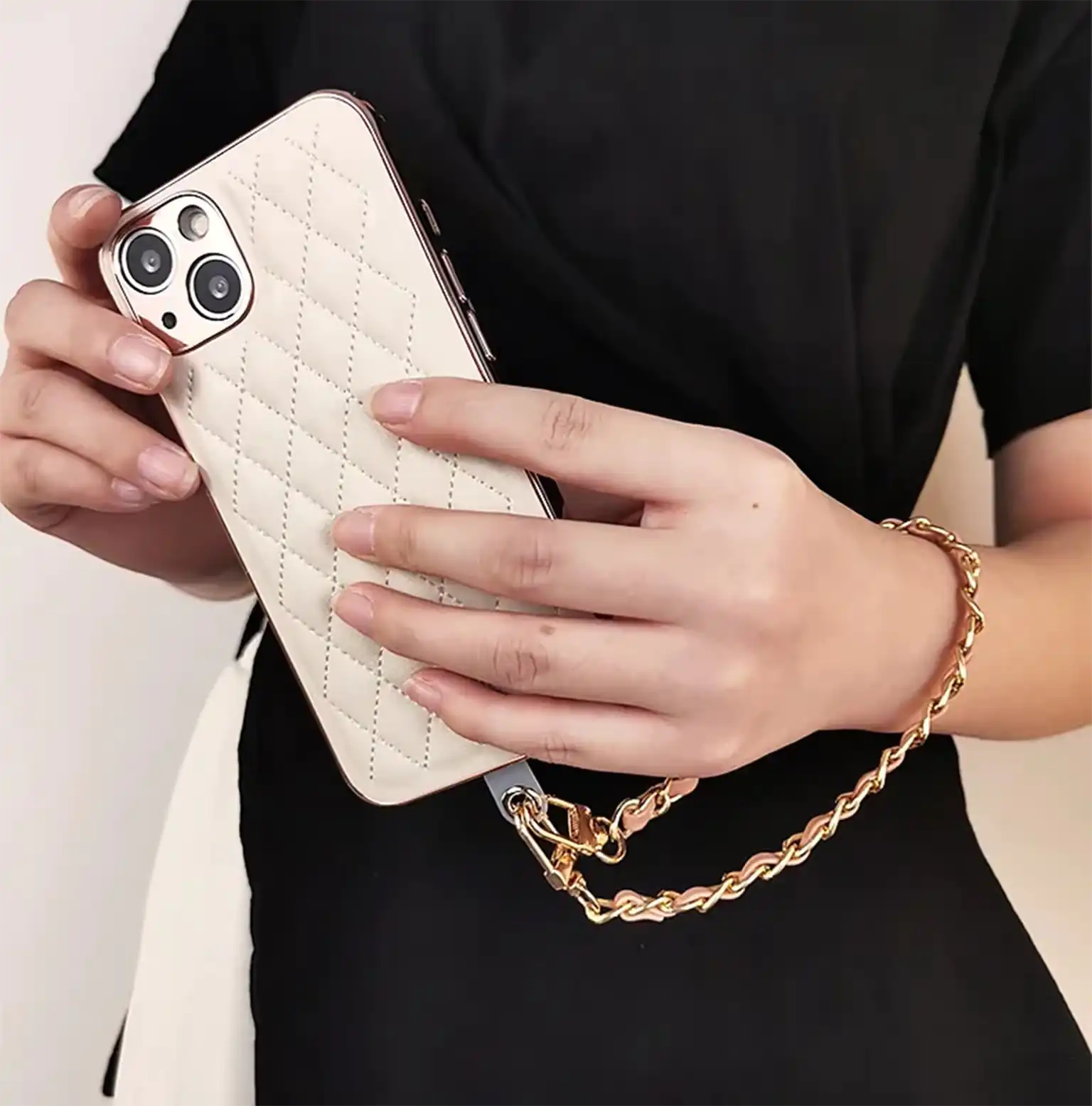 Person holding a white quilted phone case with a gold chain