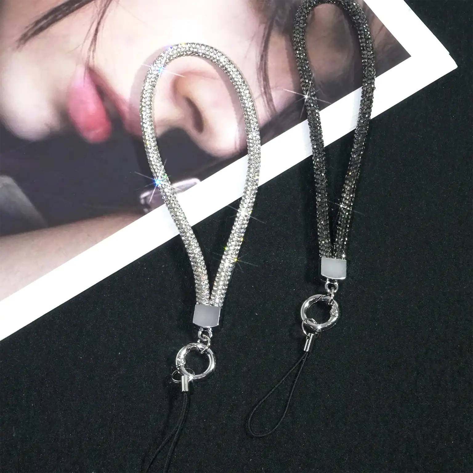 Two phone lanyards with rhinestone detailing on a black background