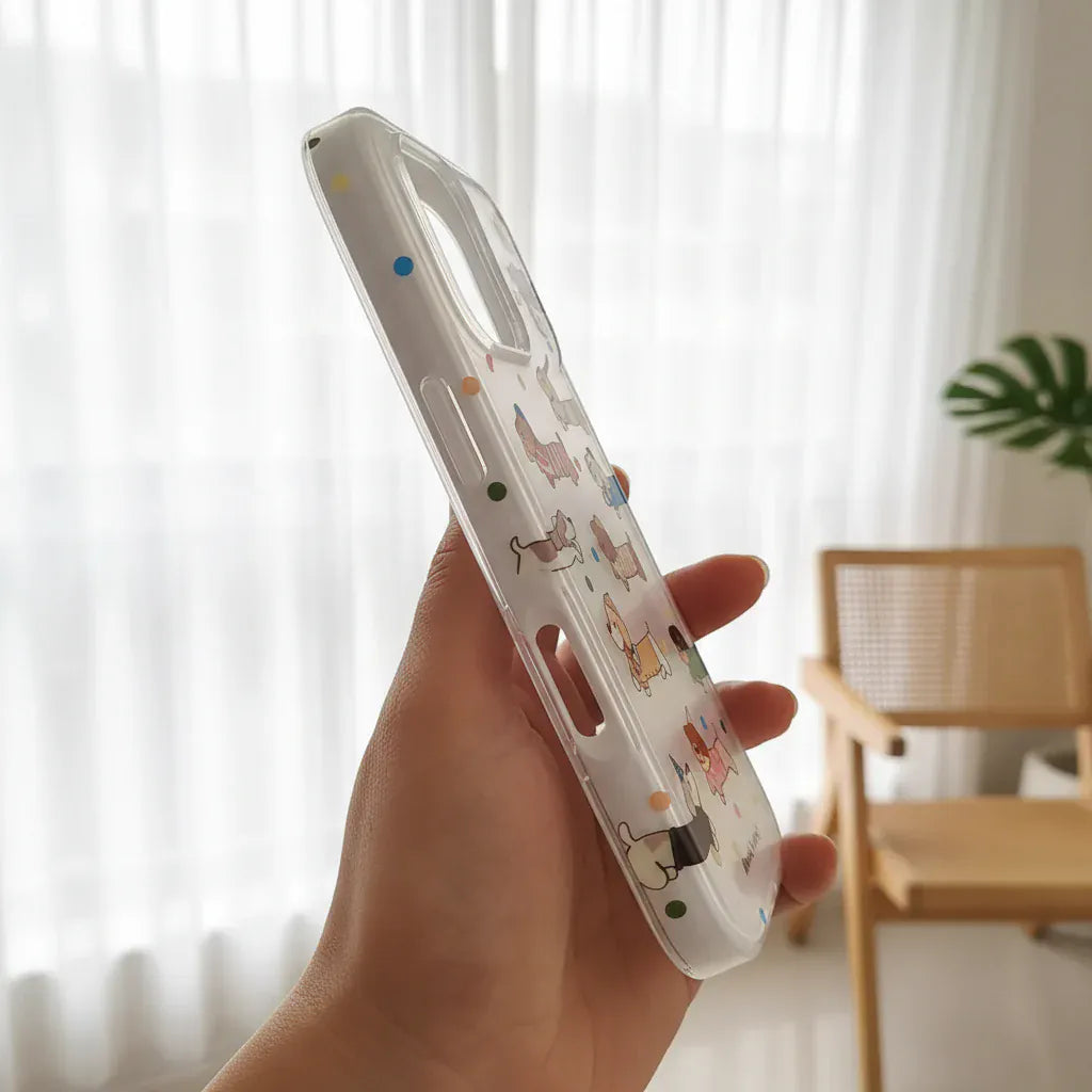 Clear phone case with cartoon designs held in a hand against a blurred green outdoor background