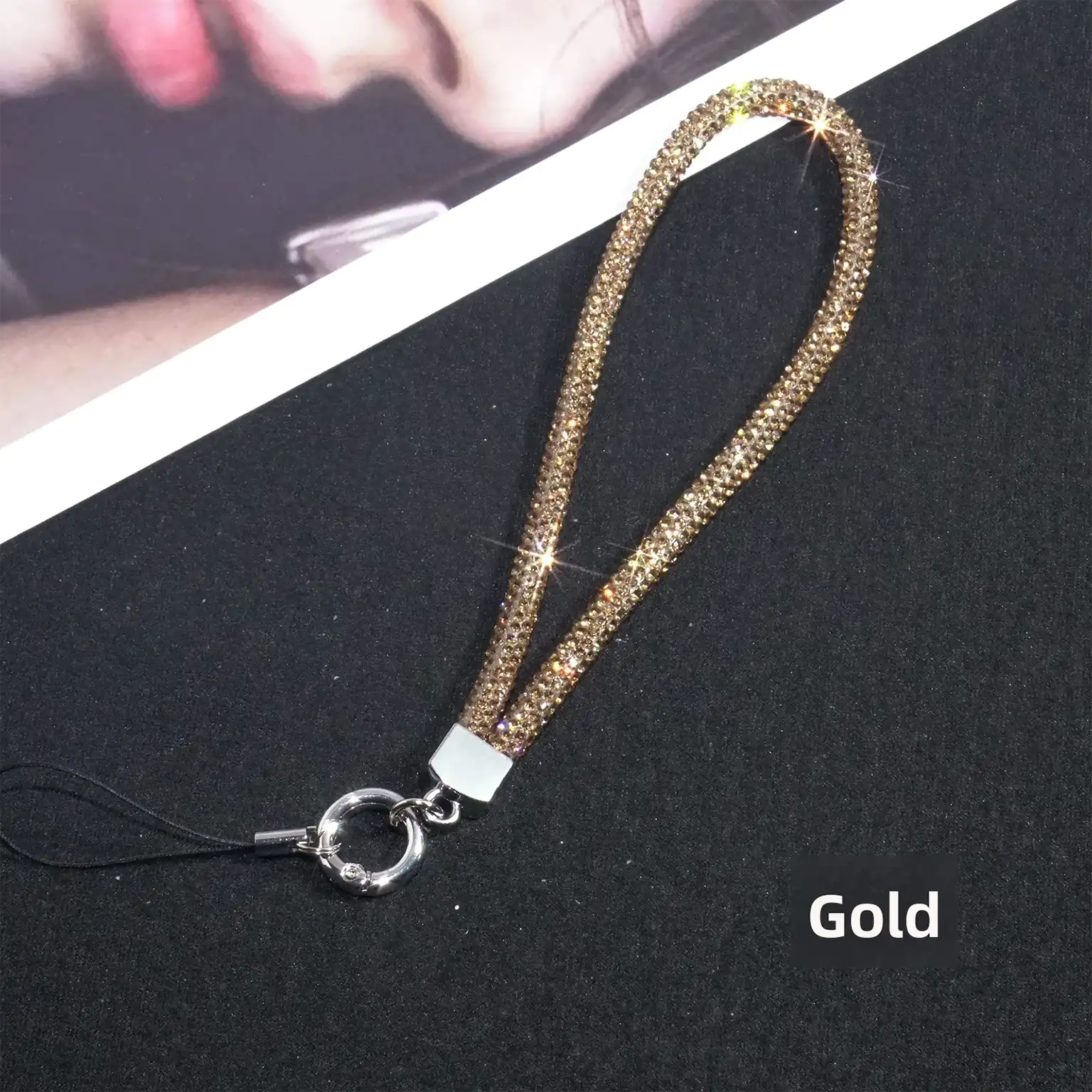 Gold phone lanyard with rhinestone details on a black background