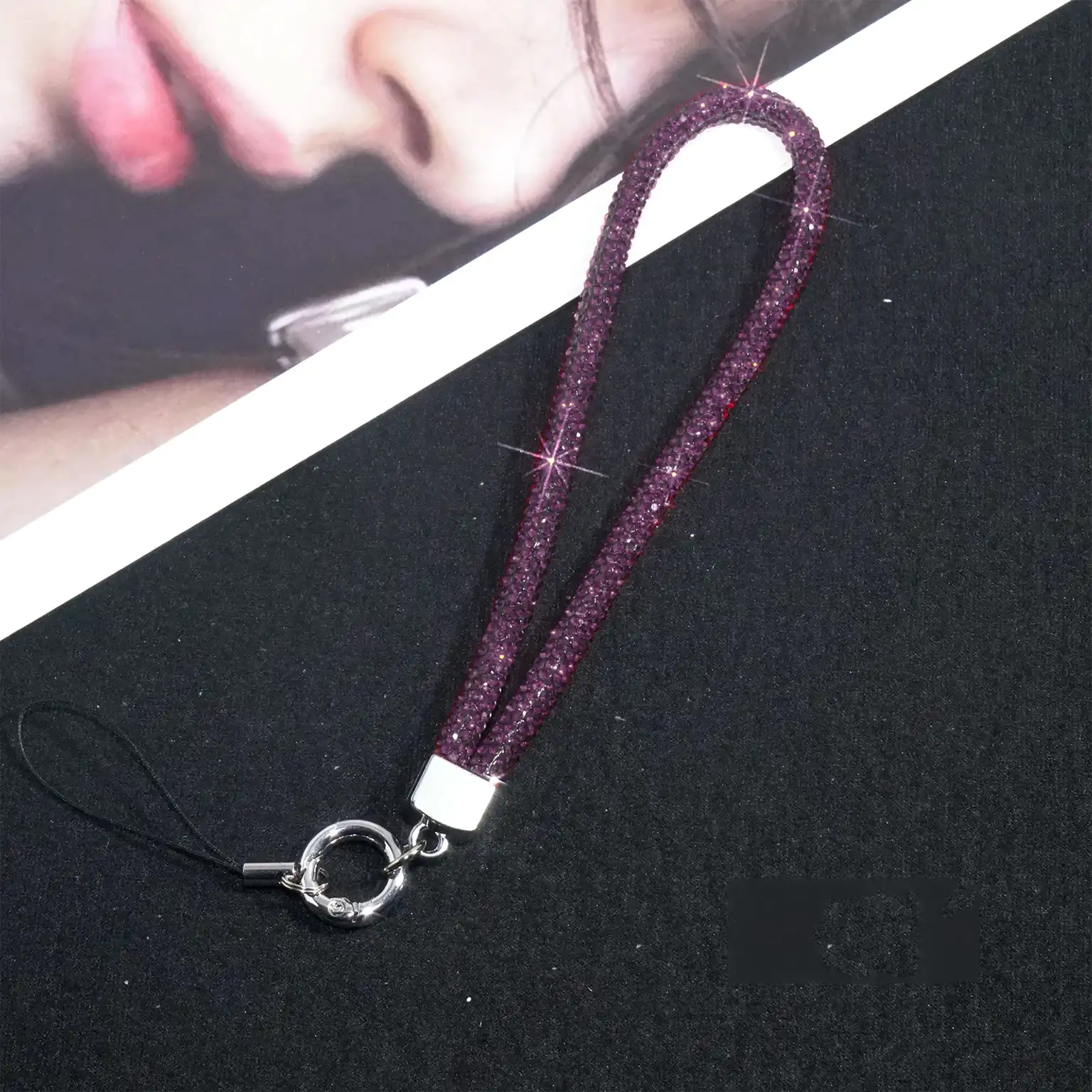 Purple glittery lanyard with a silver clip on a black surface