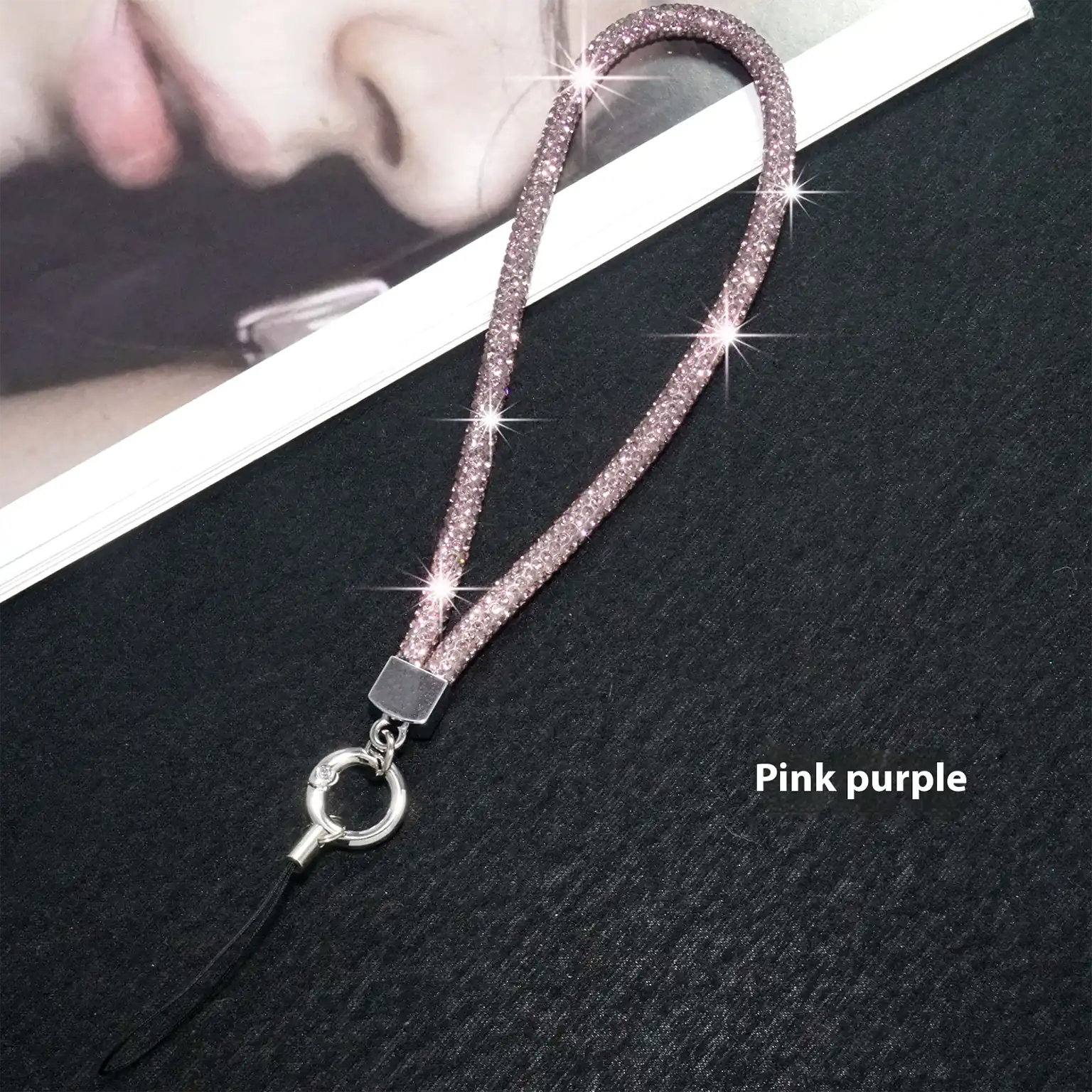 Pink purple glittery lanyard with a silver ring on a black textured background