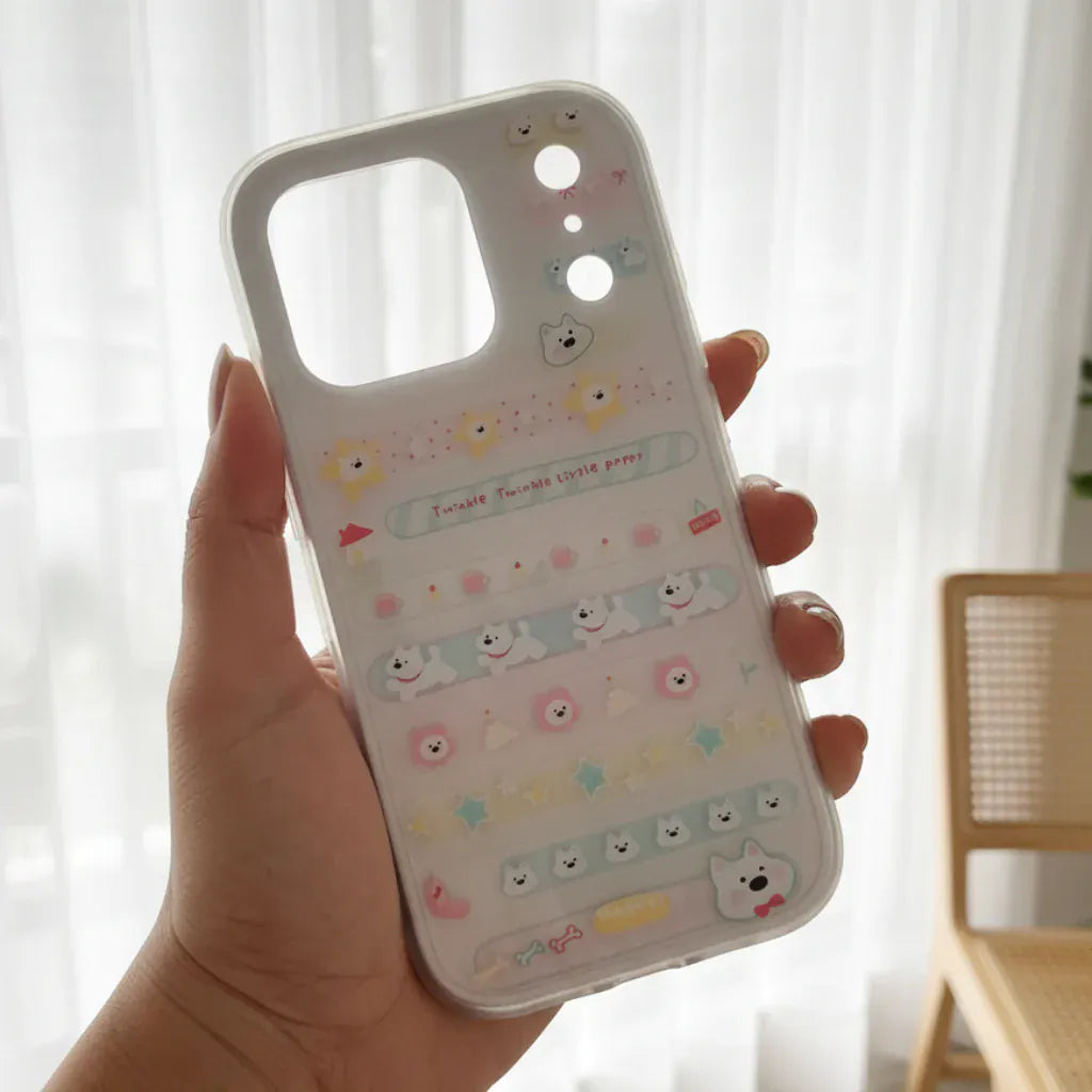 Phone case with cartoon designs held by a hand outdoors