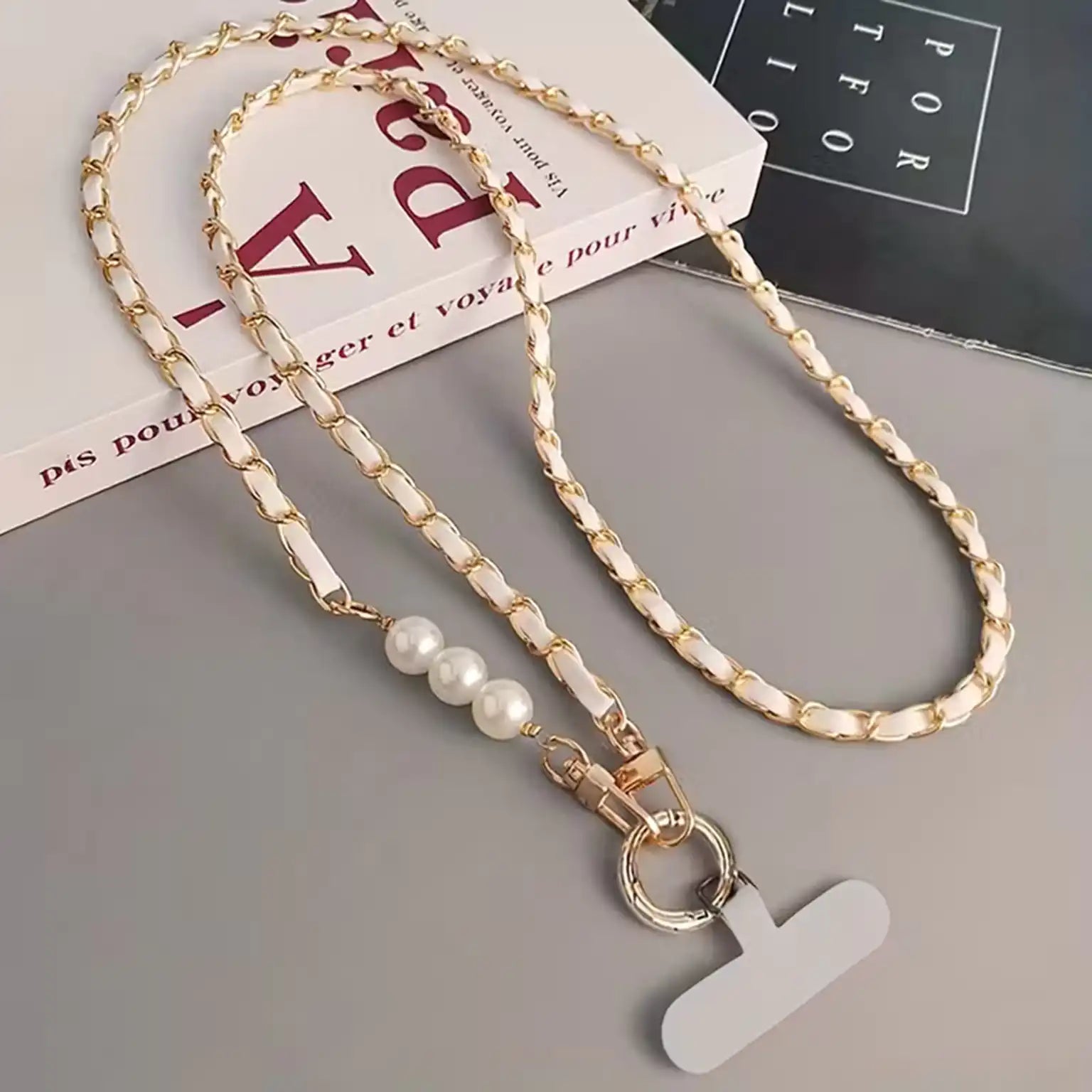 Gold chain lanyard with pearl beads and a letter 'Y' tag on a gray surface.